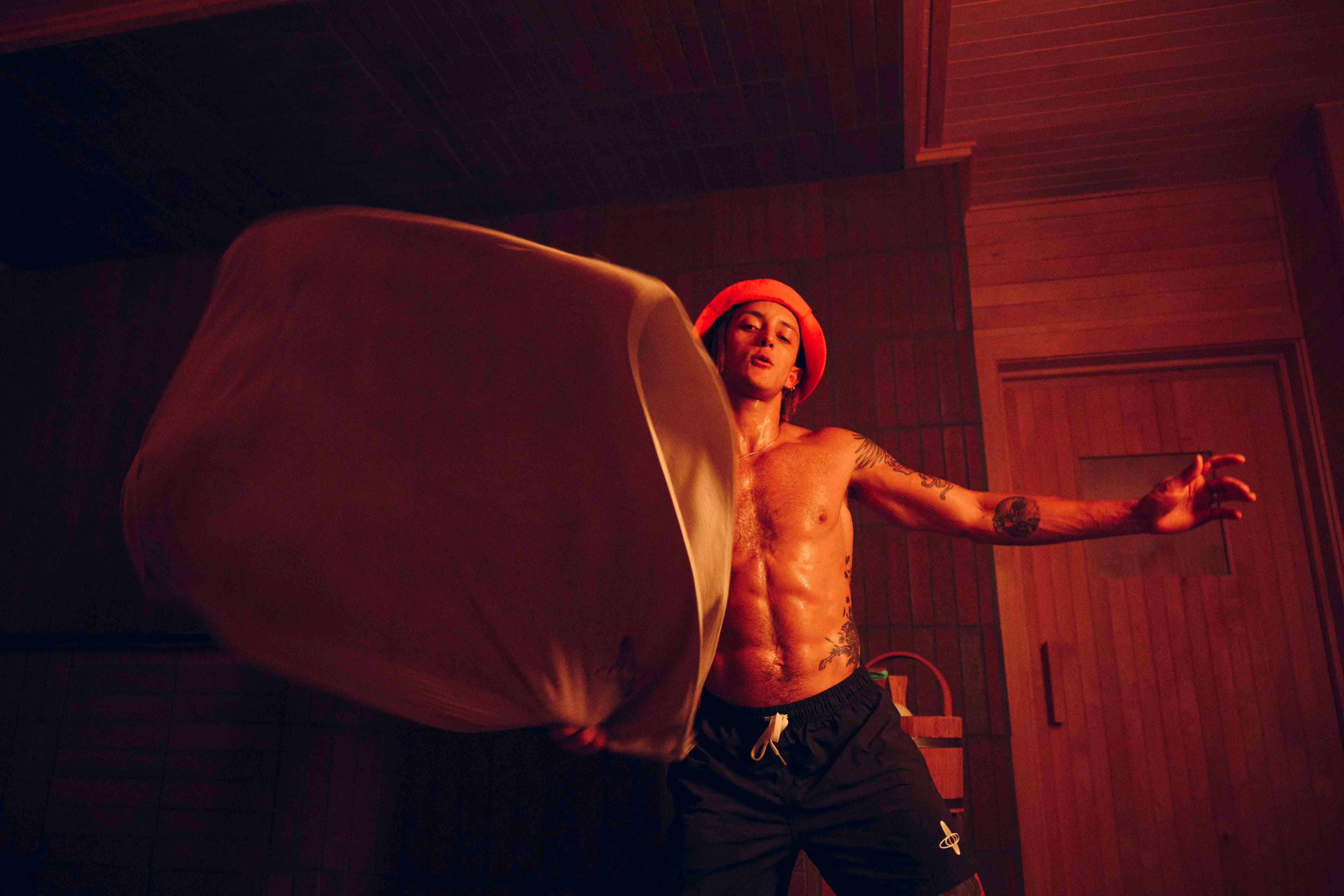 A man in the sauna uses essential oils and a towel to spread aroma, enhancing the mindfulness meditation experience for others.