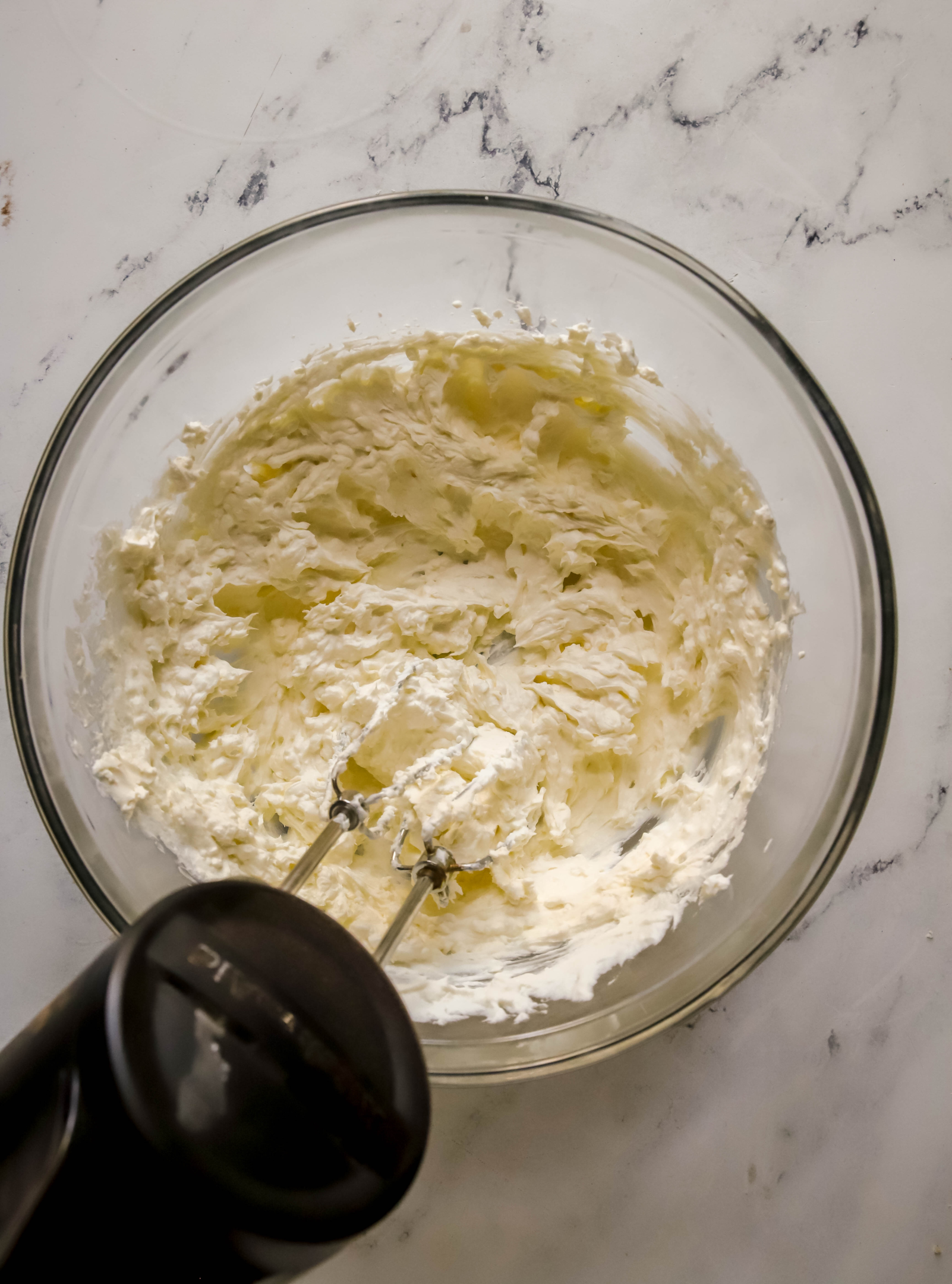 cream cheese and whipped cream being whipped together with a hand mixer