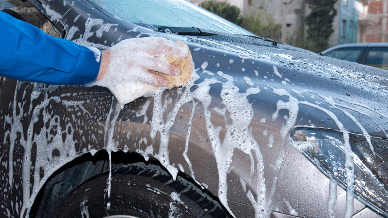 A man is gently hand washing a car.