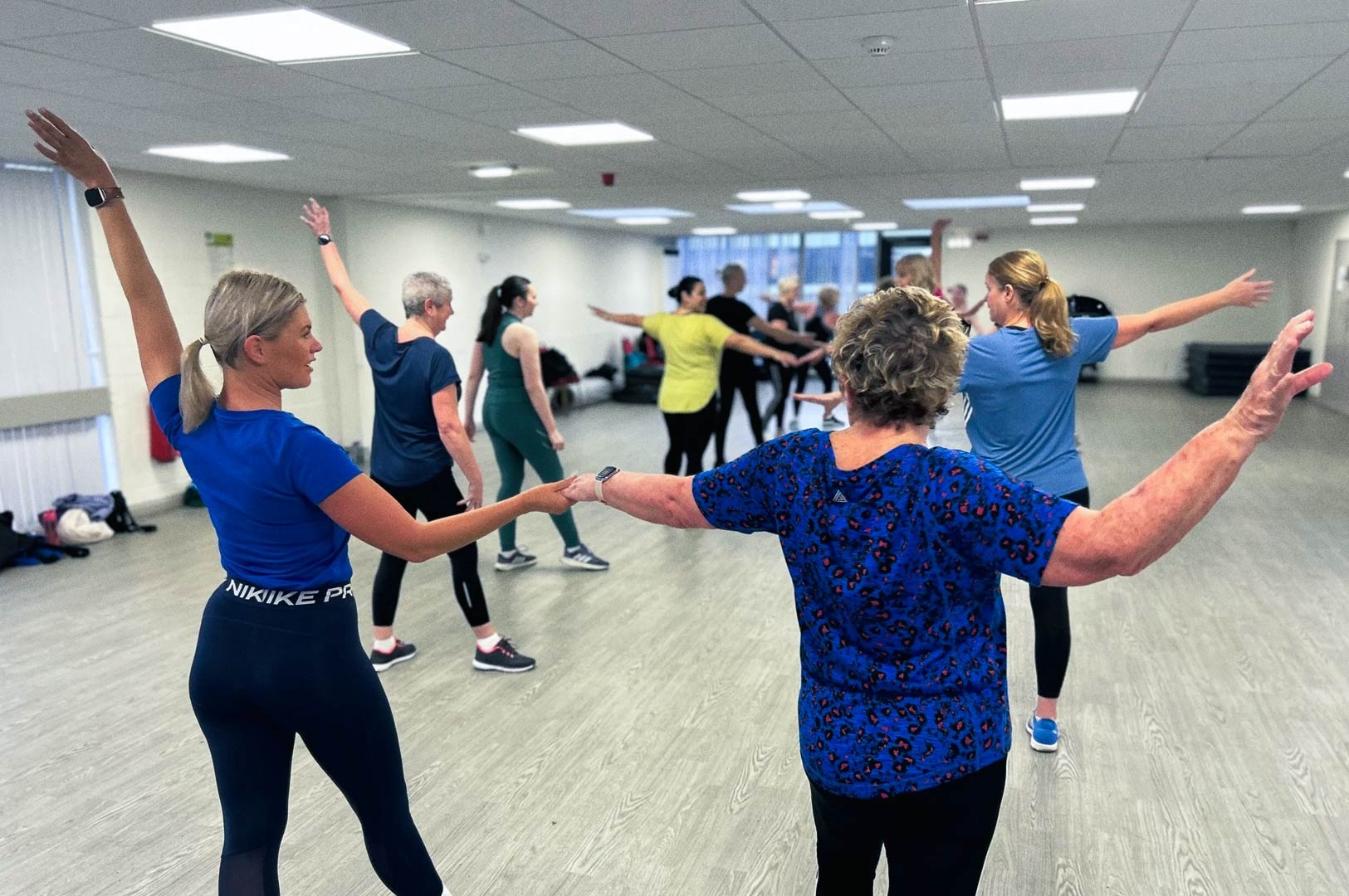 Adults participating in a group dance fitness class in a community studio.