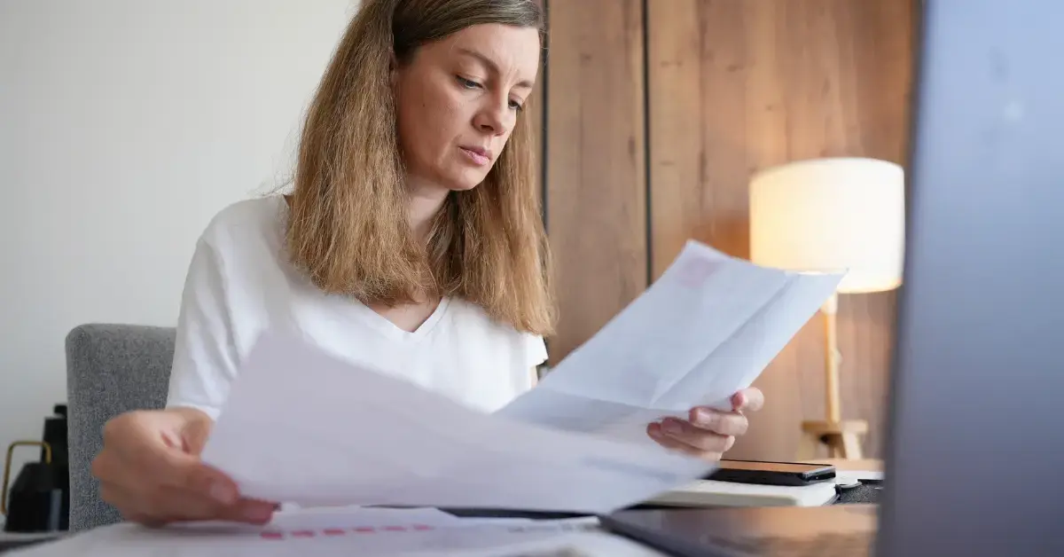 Woman reviewing IRS collection notices with tax documents and payment records.