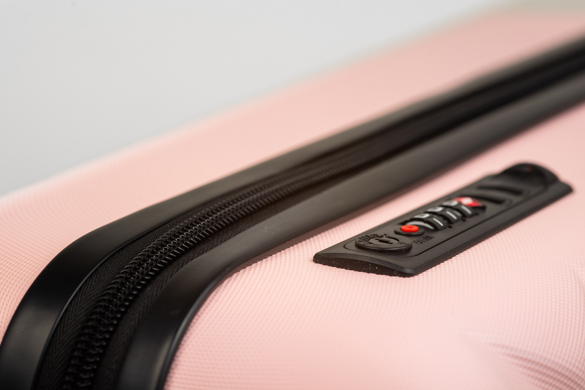 A pink suitcase with a black zipper and a lock mechanism. Tsa lost and found