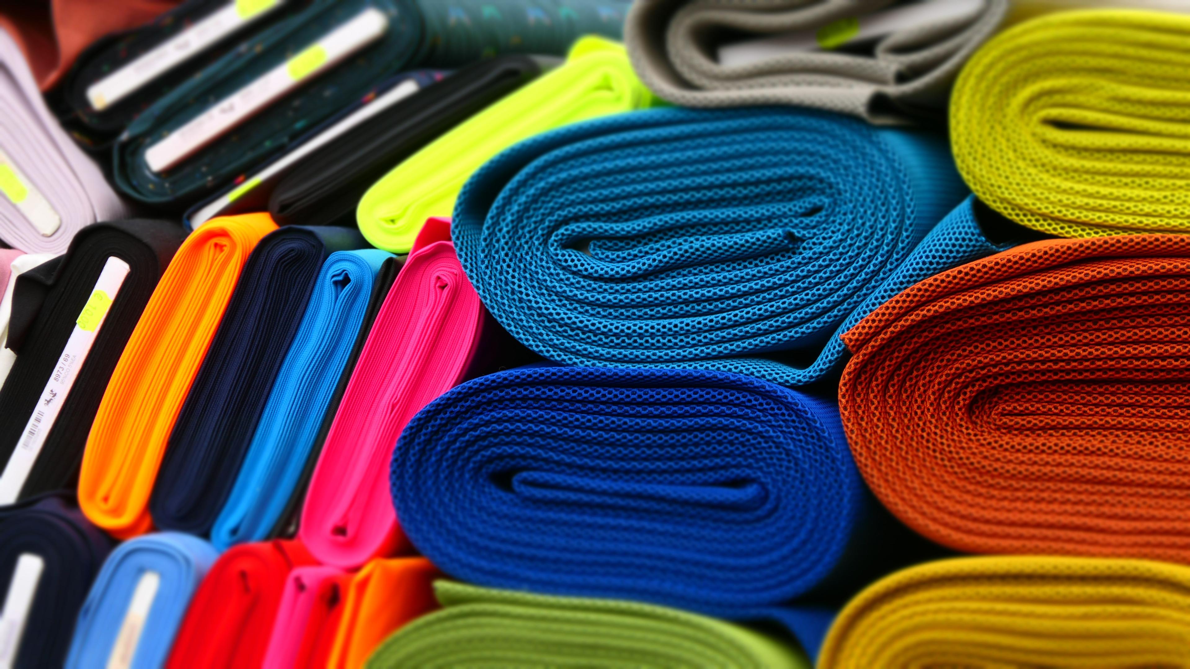 Neatly rolled fabrics grouped together displayed on top of each other.