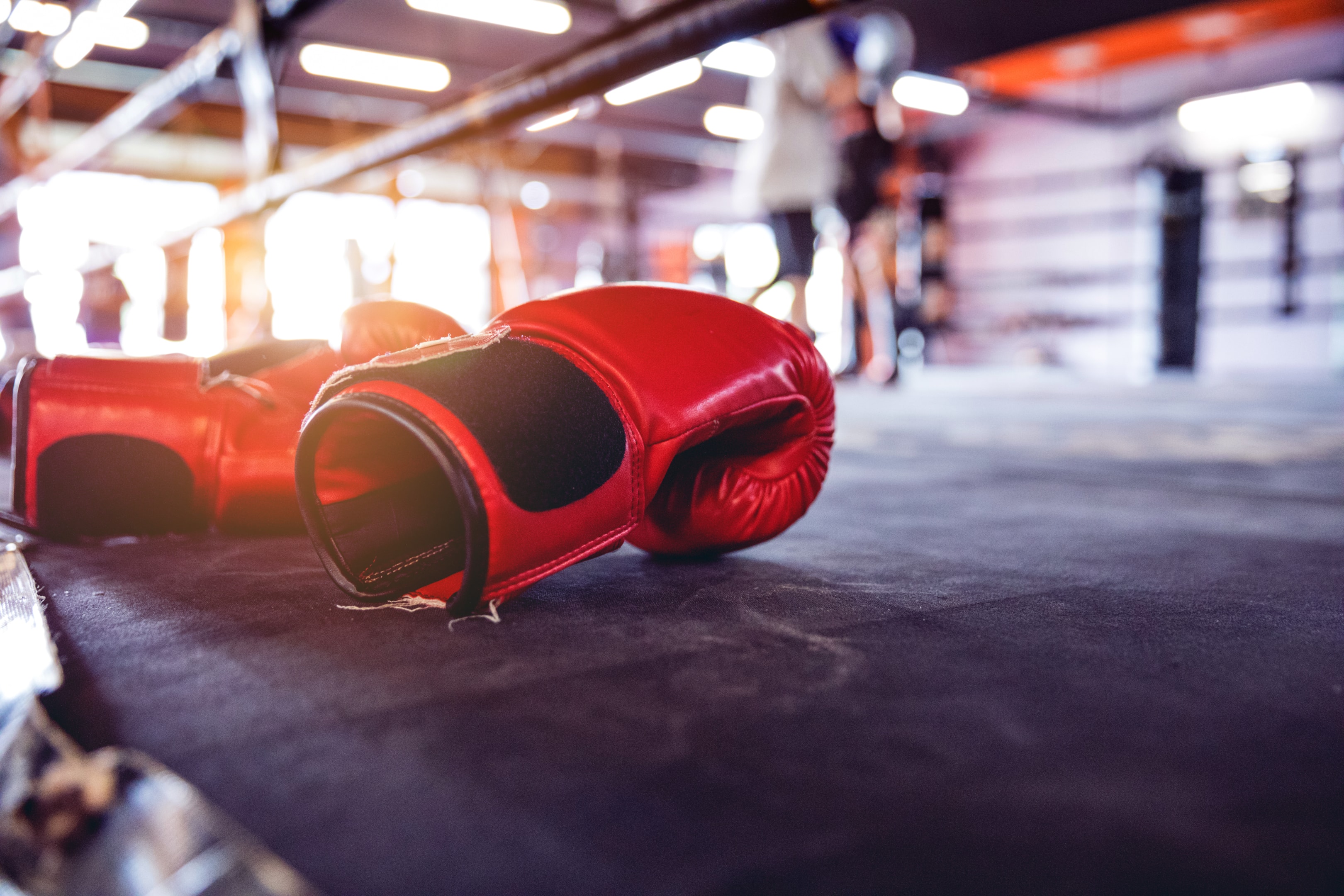 Up-close photo of red boxing gloves resting on the edge of a boxing ring.