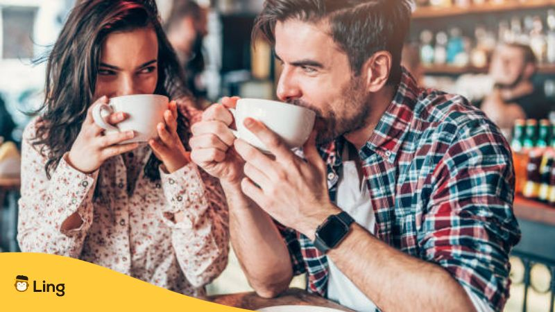 Beautiful young couple drinking coffee and looking each other