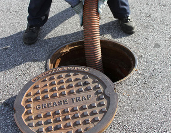 A technician disposing of grease trap waste in a safe manner
