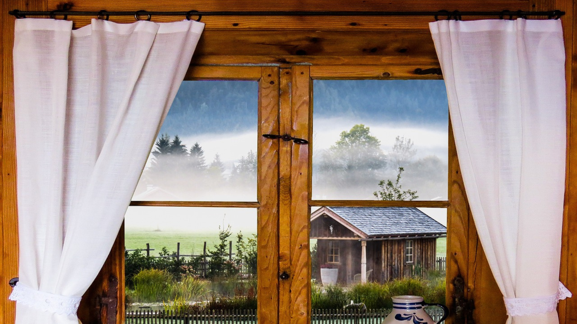 Heavy wood, farmhose-style window with white cheese cloth cutains on a slim, black pole