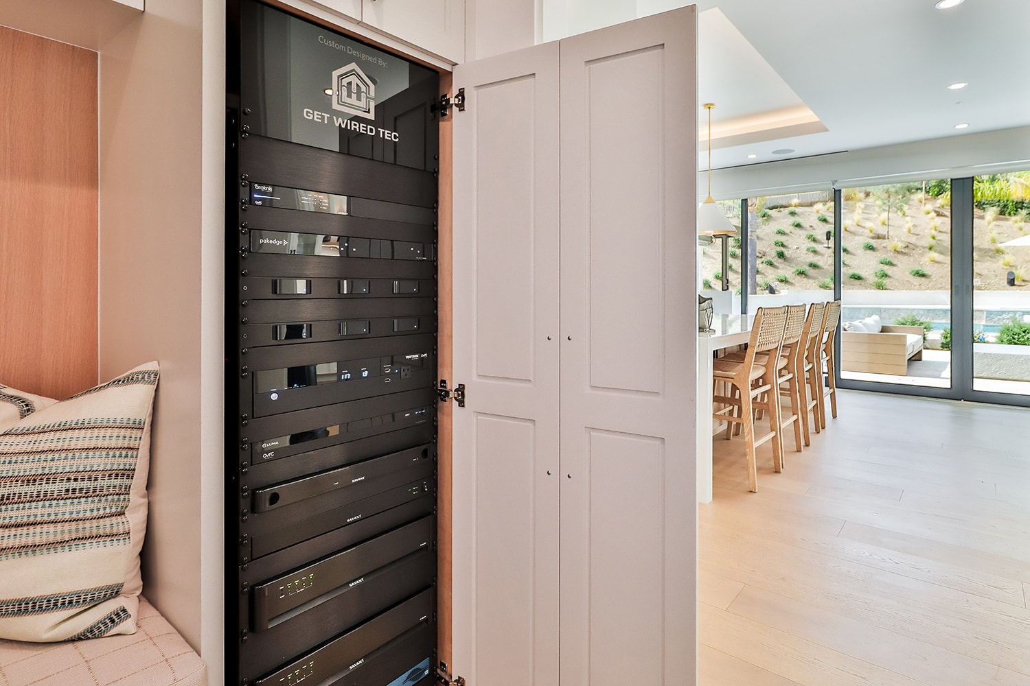 The image depicts an organized network rack cabinet featuring neatly arranged cables and networking equipment, showcasing a smart home infrastructure that supports strong Wi-Fi and various smart systems. This setup highlights the importance of pre-wiring for future upgrades and a seamless smart home experience in new construction or luxury homes.