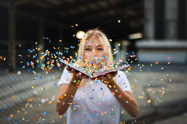 Bringing confetti and blowing it at the camera is a fun senior picture idea, like in this picture of a girl blowing confetti off of a book.