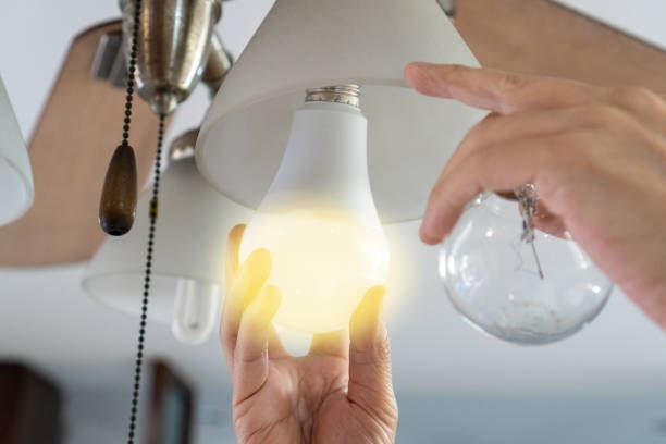 A person replacing traditional bulb with an environmental-friendly LED light. 