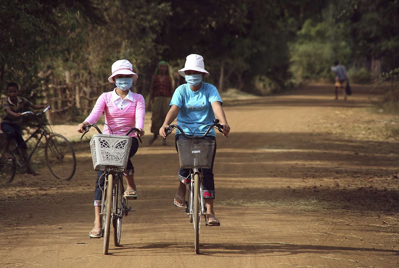 An image of two people riding bicycles while wearing face masks to protect against air pollution.