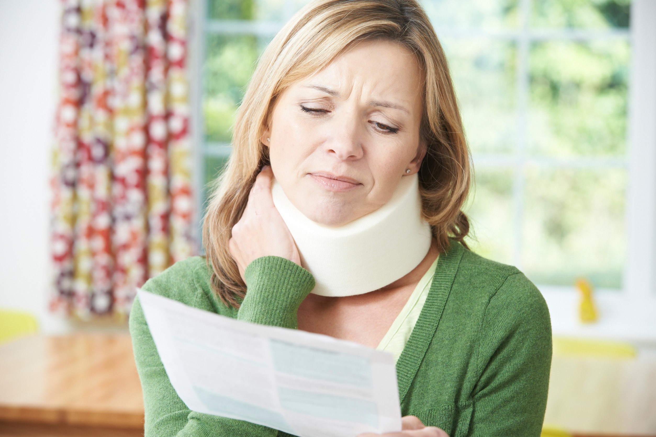 A woman with severe neck injuries reads a medical report while wearing a neck collar