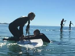 woman trying to stand on a paddle board