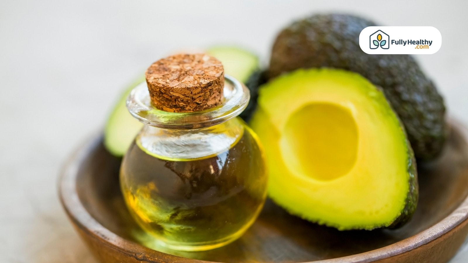 Small glass jar of avocado oil with fresh halved avocado
