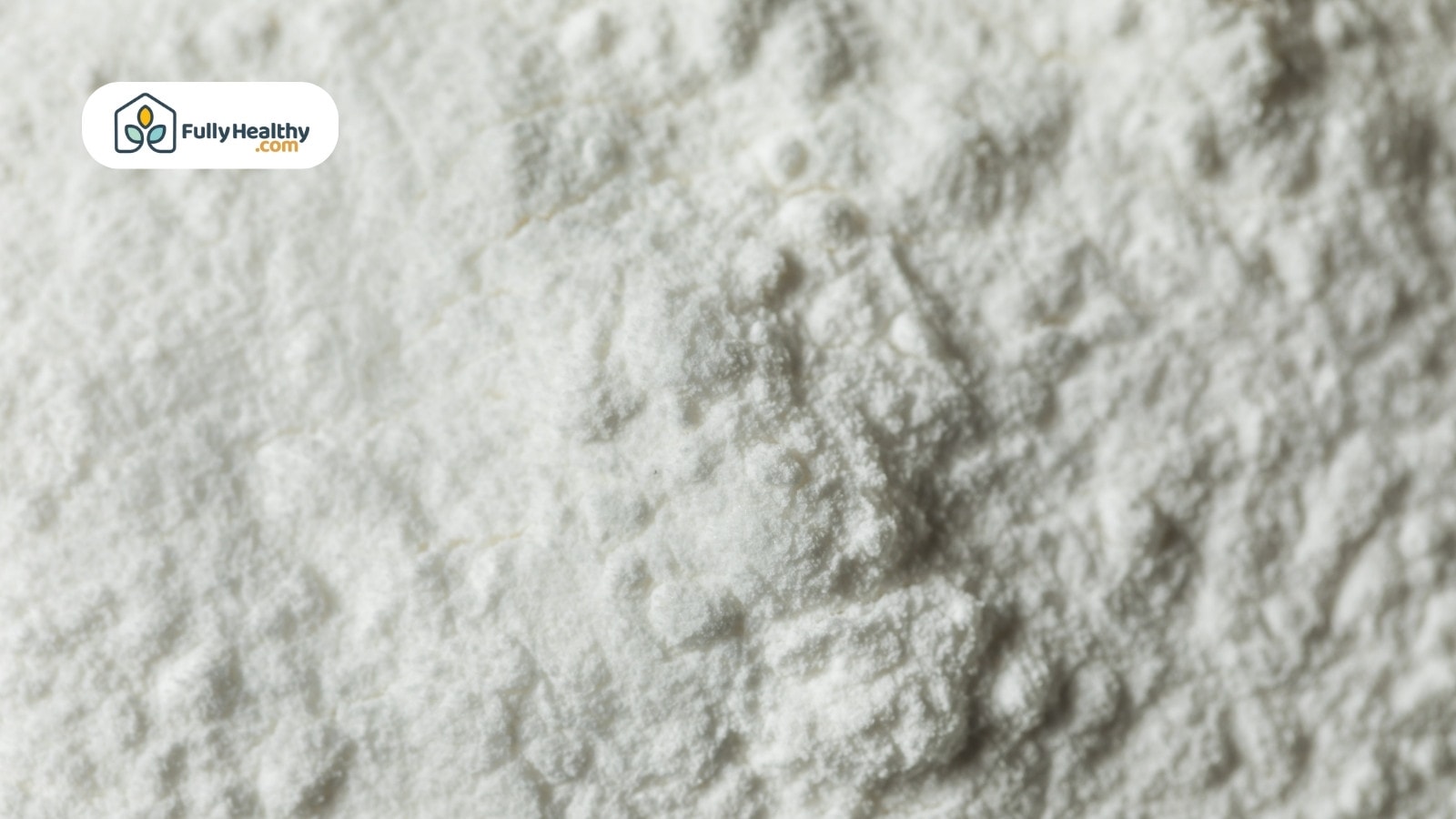White ceramic bowl filled with cornstarch powder beside metal spoon