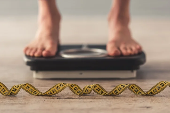 Tape measure and a man standing on weighing scale