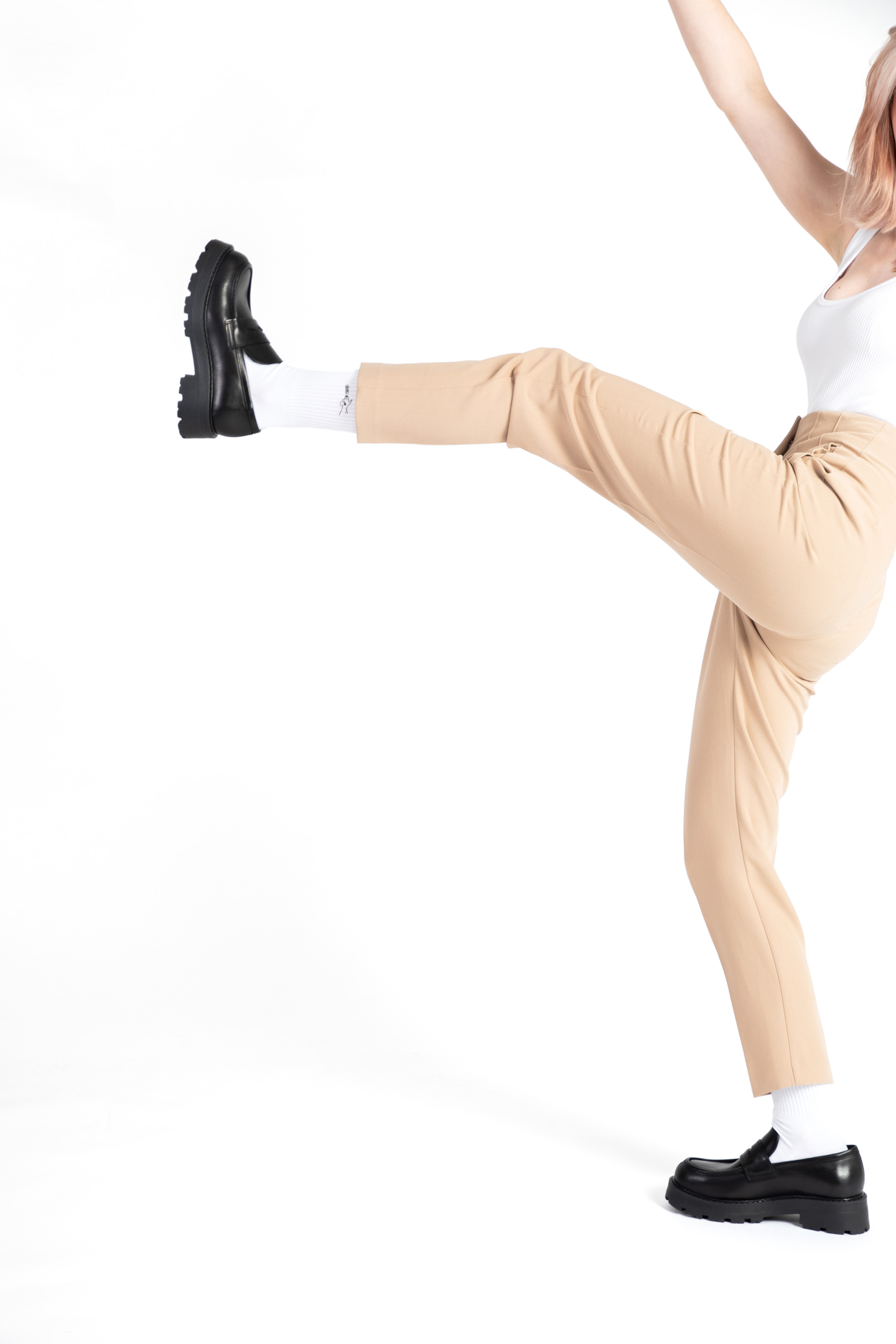 A female model wears black leather loafers with a pair of white embroidered crew socks.