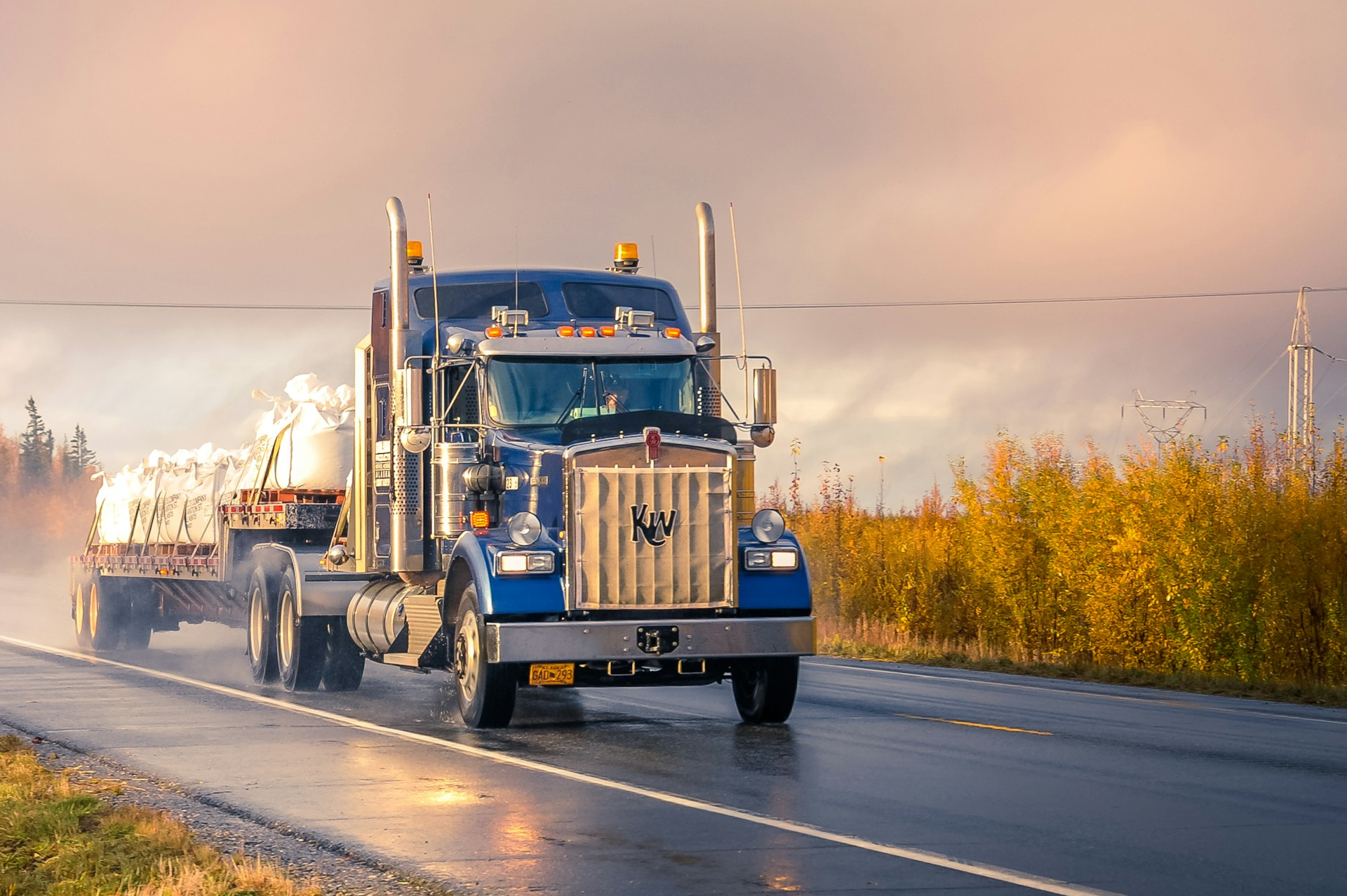 a semi truck driving on the road during sunset
