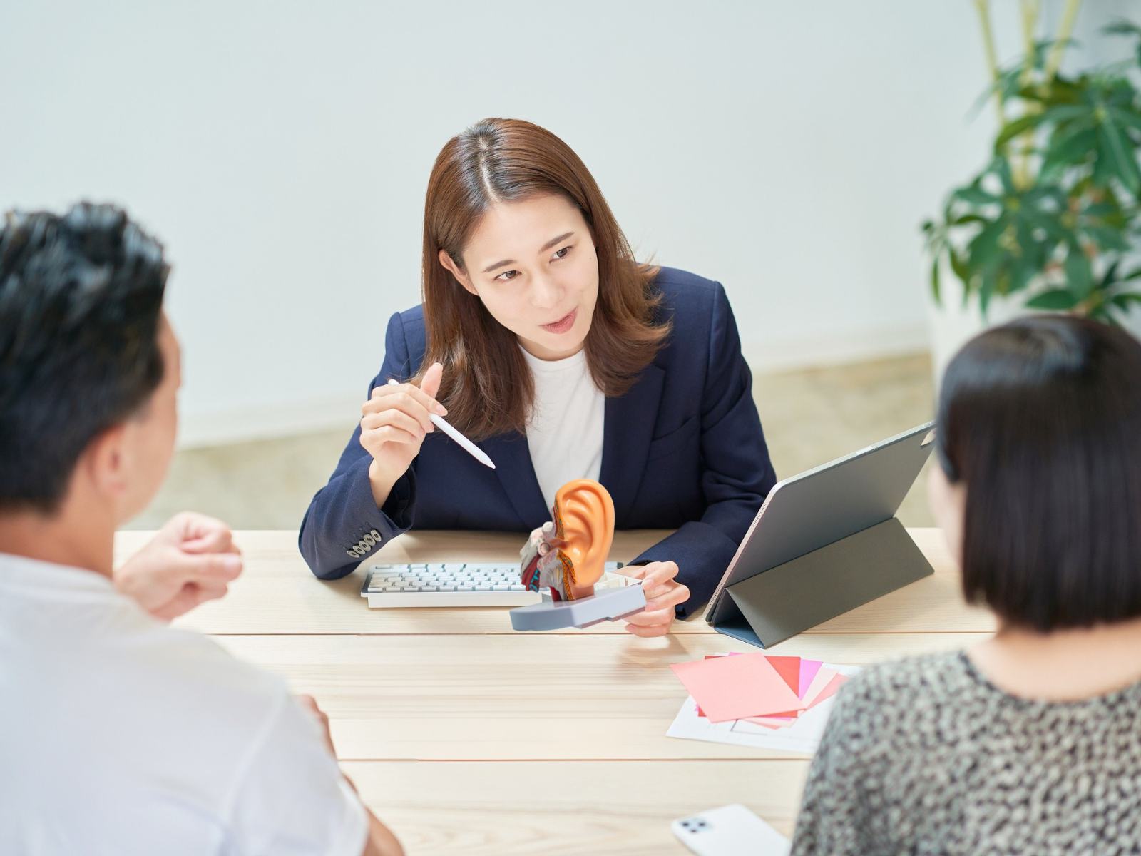 The image shows an audiologist in a clinical setting engaged in a friendly consultation with a senior patient, discussing their hearing needs and potential hearing aid technology options. The interaction highlights the importance of personalized hearing healthcare and the various hearing aid technology levels available to improve sound quality and better speech understanding.