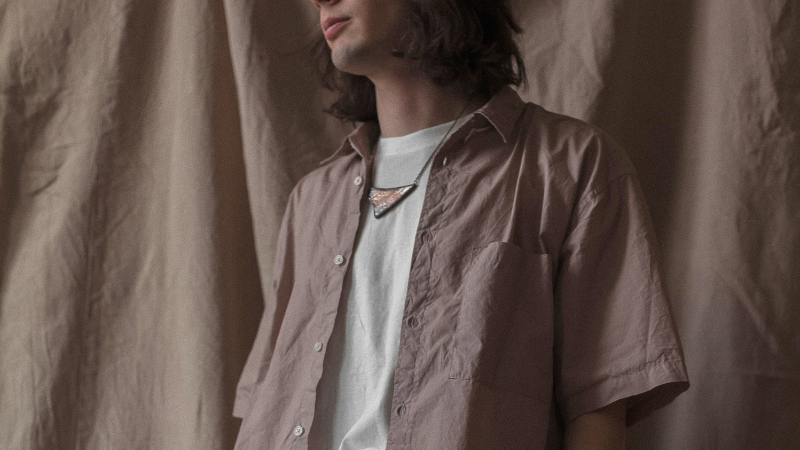 A person in a fashionable jute shirt standing against a wall