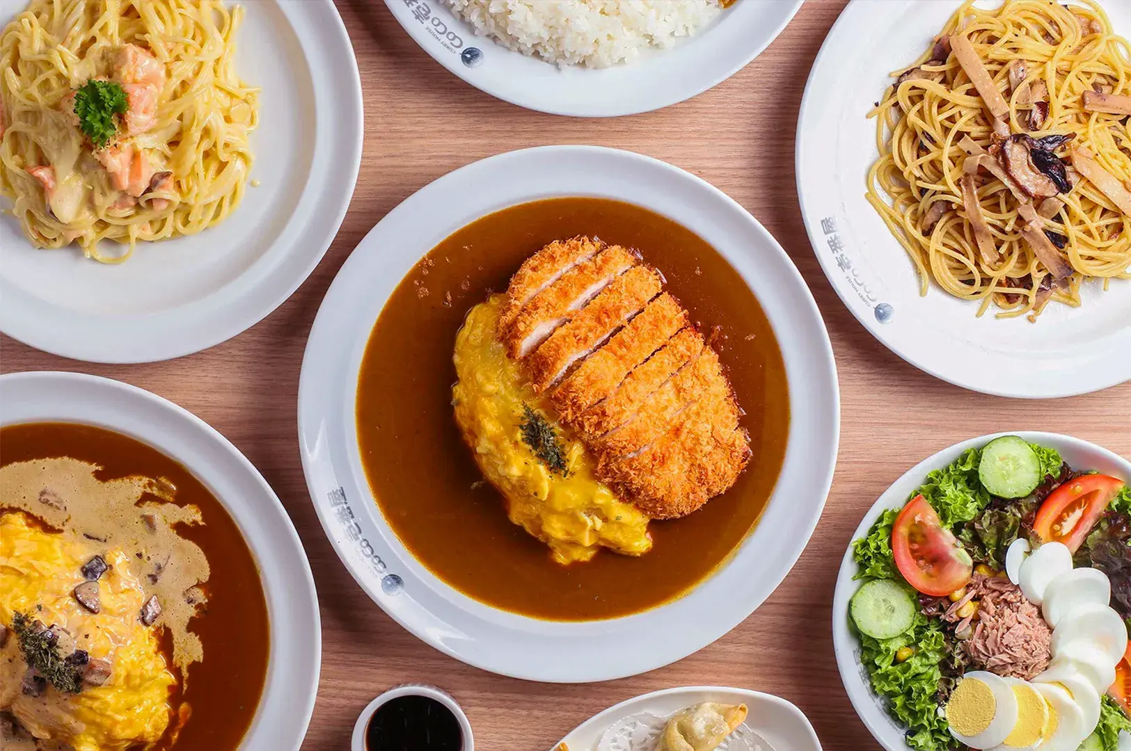 Close-up food photo of Japanese katsu curry featuring crispy breaded pork cutlet sliced over rice, topped with creamy sauce and served with rich brown curry on a white plate.