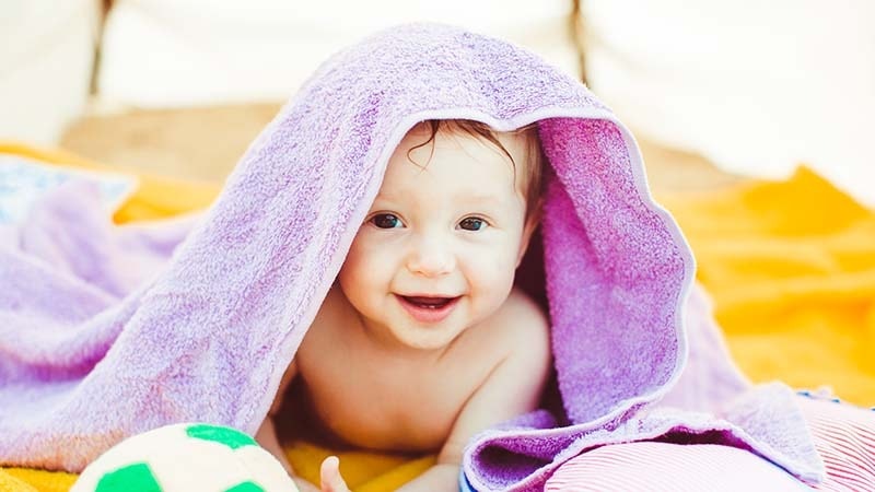 A baby in a purple child safe microfiber towel