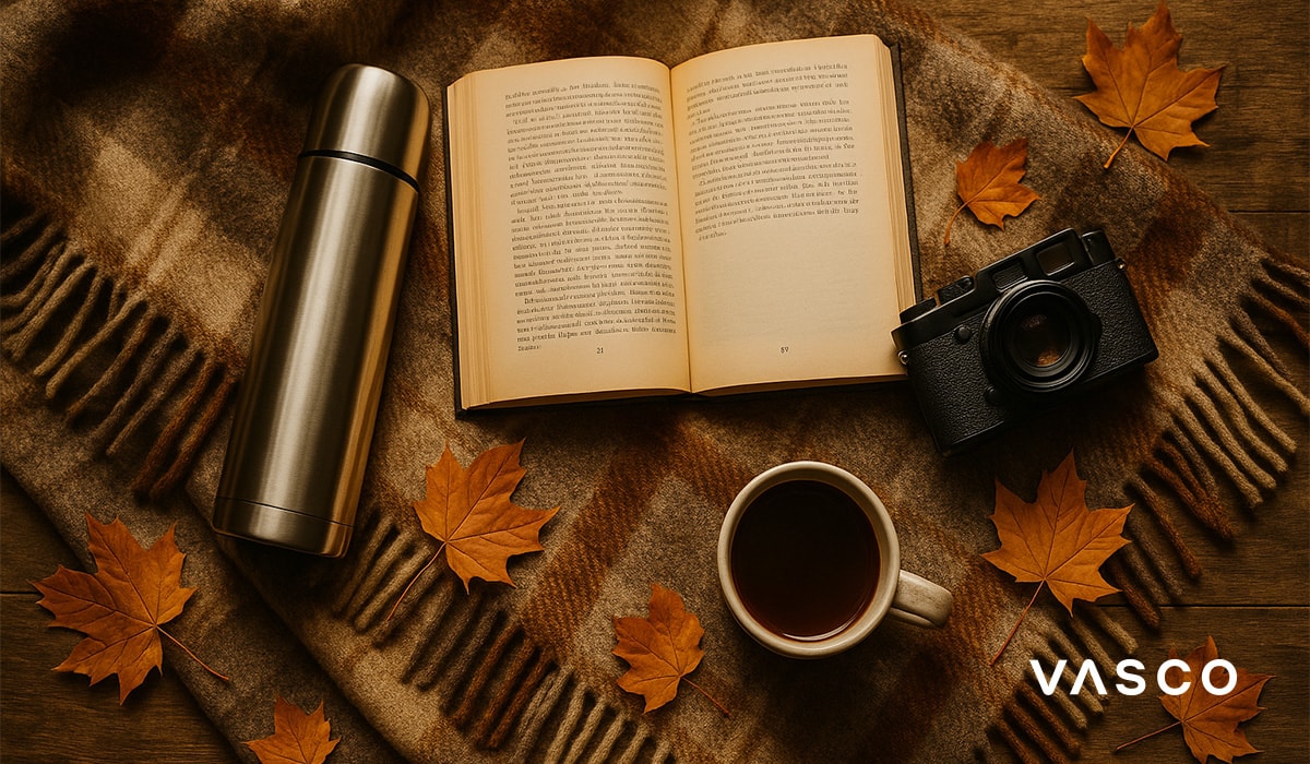 Mise en scène automnale cosy : livre, appareil photo, thermos et tasse de thé.