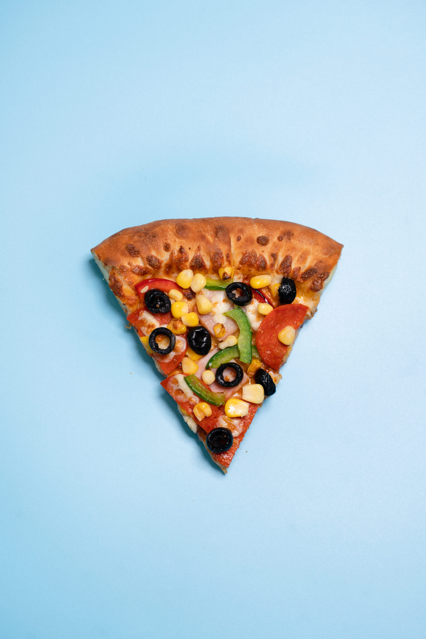 Commercial photo of slice of pizza against a blue background