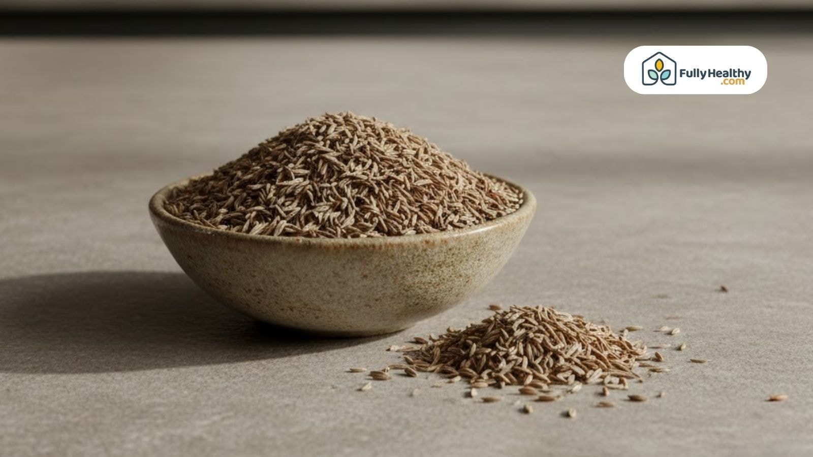 Bowl filled with whole cumin seeds showing yellow brown longitudinally ridged texture.