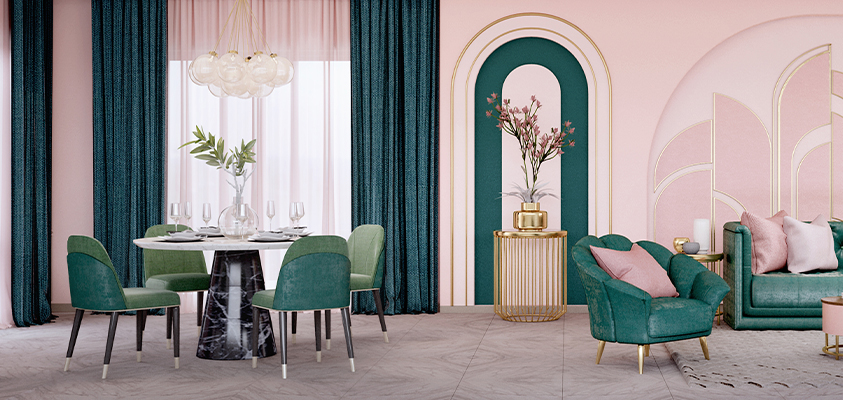 A bright pink and deep green living and dining combo room. Green accent chairs are arranged around a black and white marble dining table. A green clamshell chair and sofa with pink throw cushions are arranged around a pink and gold coffee table. Between both settings is a gold coffee table with a gold vase and pink flowers, and the walls feature decorative moulding with a gold trim.