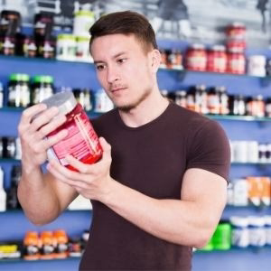 A person holding a protein shake and looking at the label to check protein content per serving