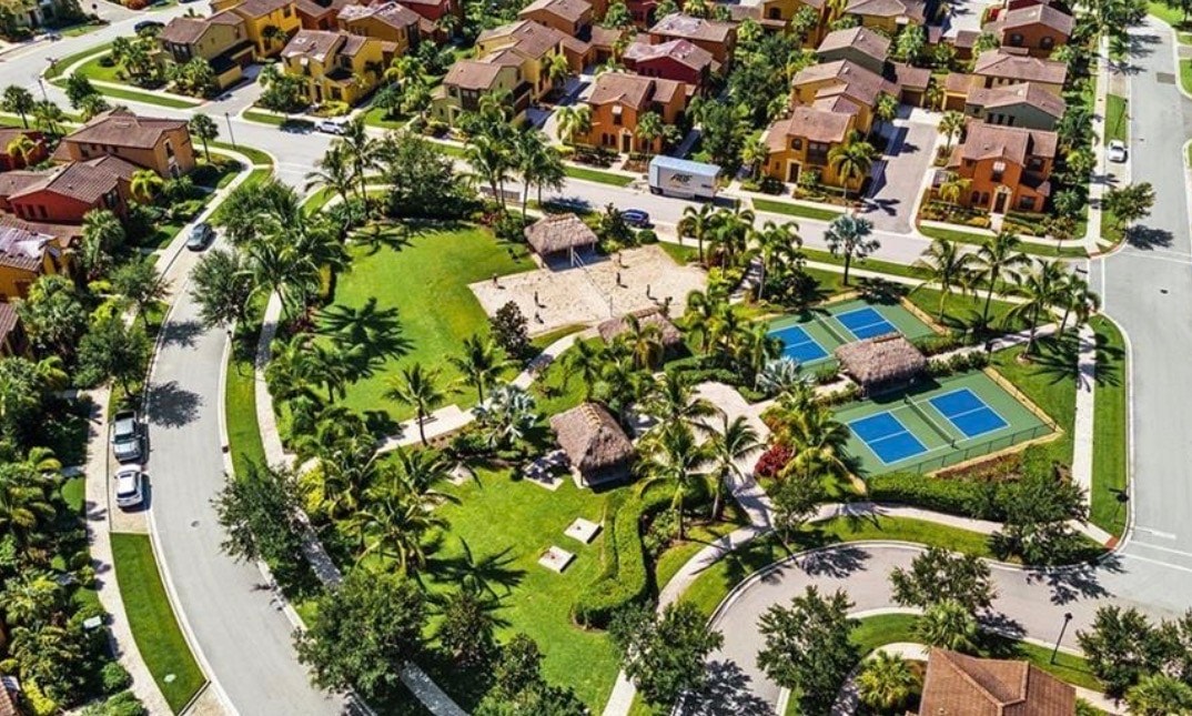 This image depicts a Mediterranean-style single family home located in the prestigious Paseo community of Fort Myers, featuring a spacious covered lanai and a beautifully landscaped front yard. The home exemplifies resort-style living with its inviting architecture and well-maintained surroundings.