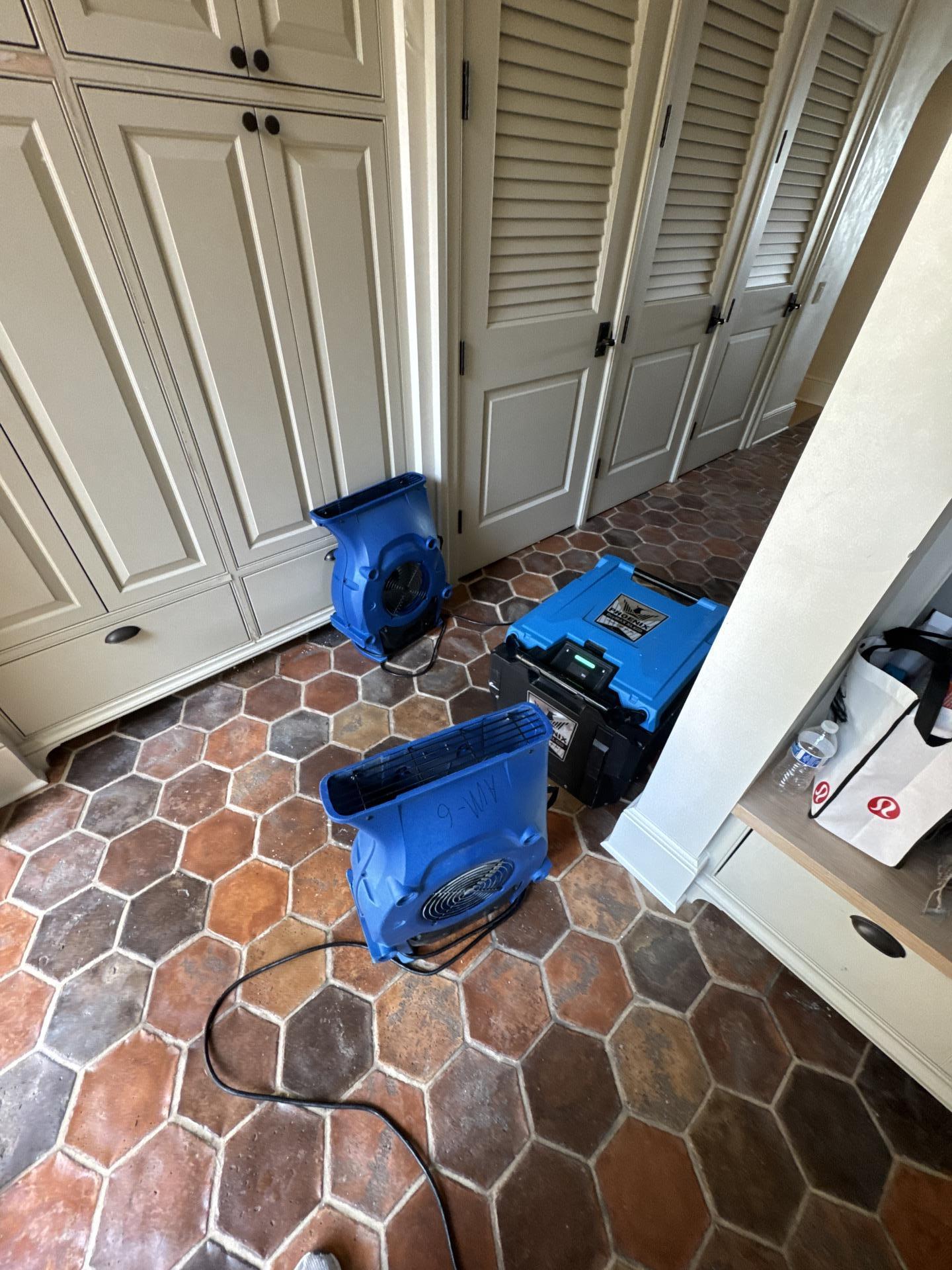 The image shows industrial fans and dehumidifiers set up in a room with wet carpeting, actively drying the space to prevent mold growth and address water damage. The equipment is essential for effective restoration after flooding, helping to remove standing water and moisture from the affected areas.