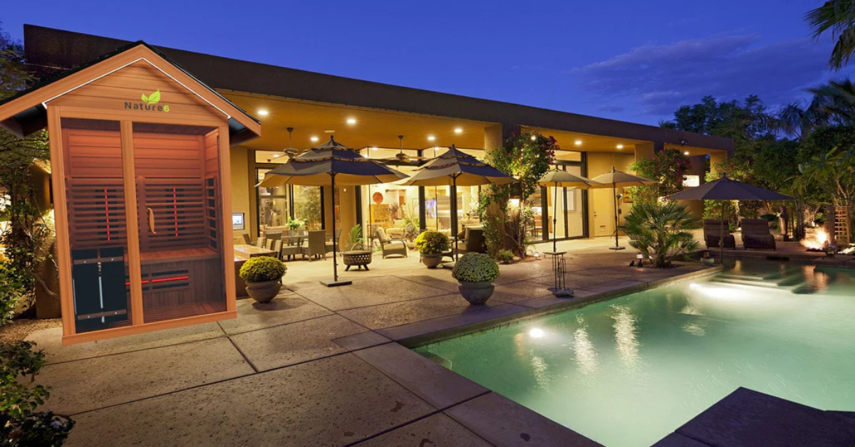 A backyard at night with a lit up sauna and pool.