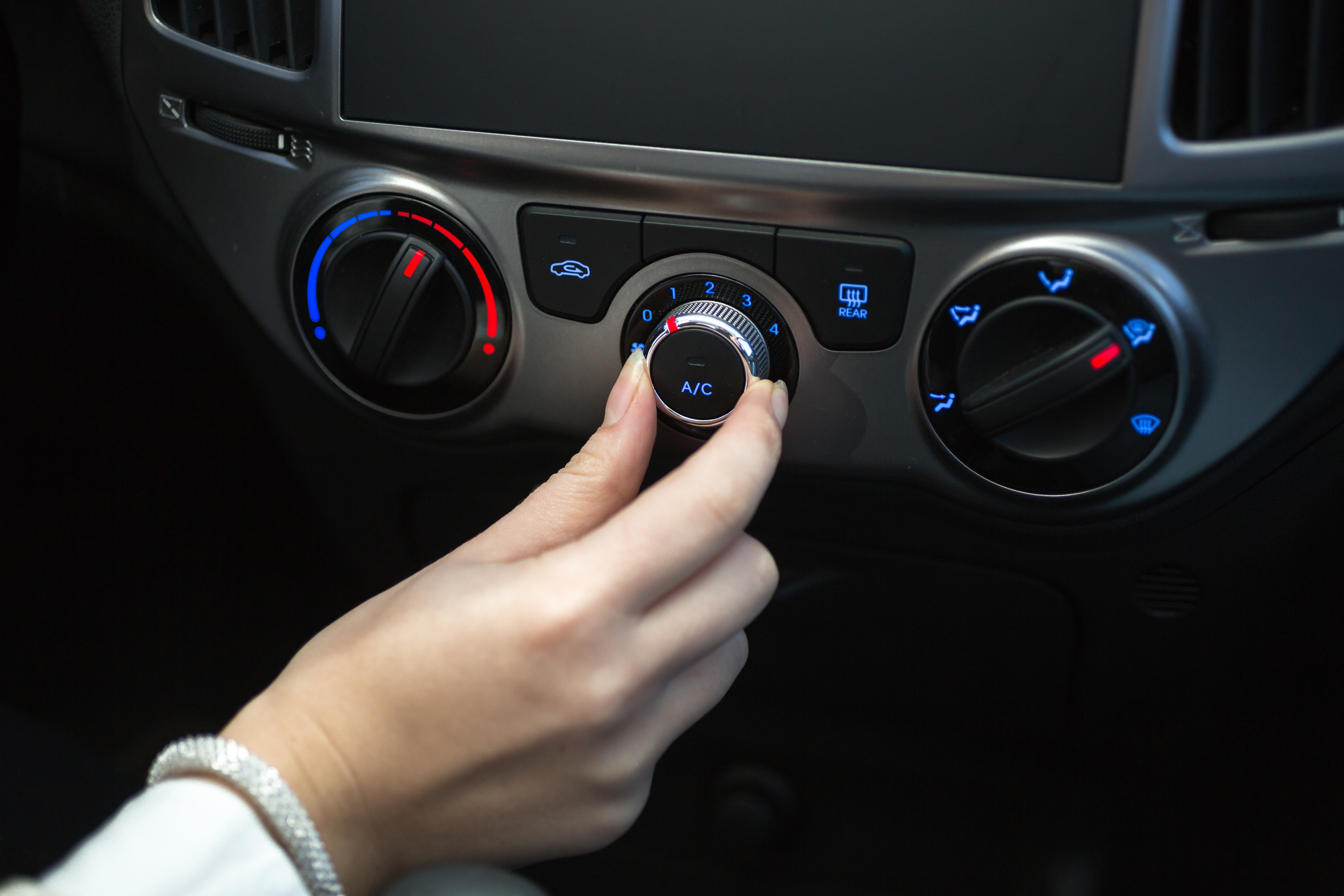Hand adjusting car's air conditioner control panel. Air recirculation in off.