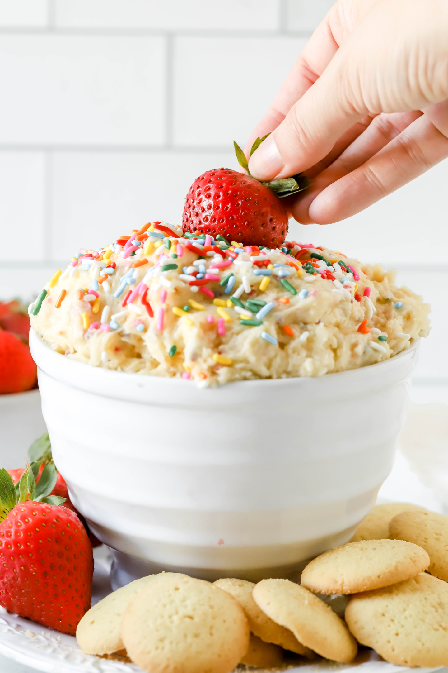 strawberry being dipped into a bowl of cake batter dip
