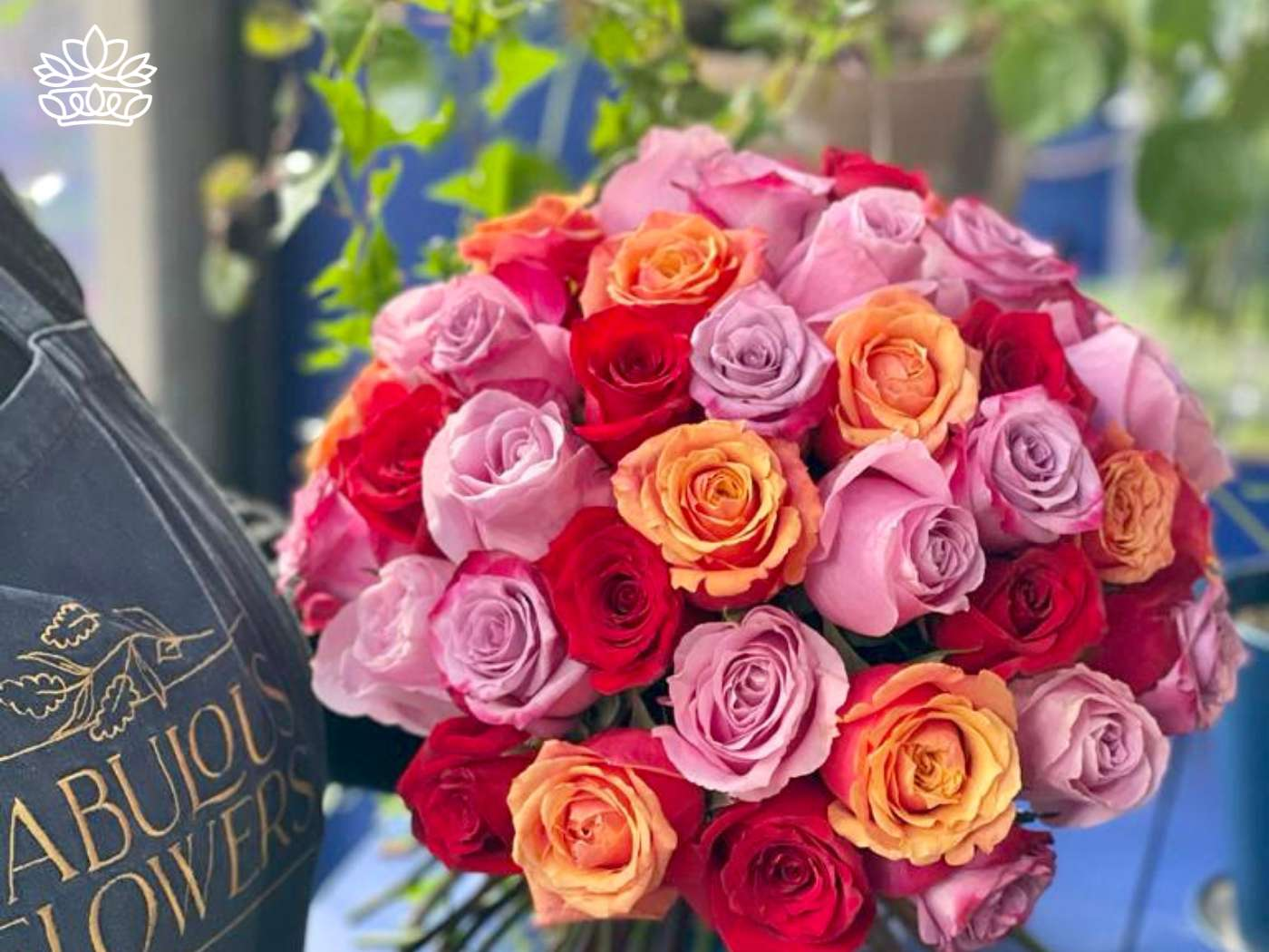 An excited florist holding a vibrant bouquet of roses you deserve in shades of pink, orange, and red, epitomizing the exquisite selection at Fabulous Flowers and Gifts.