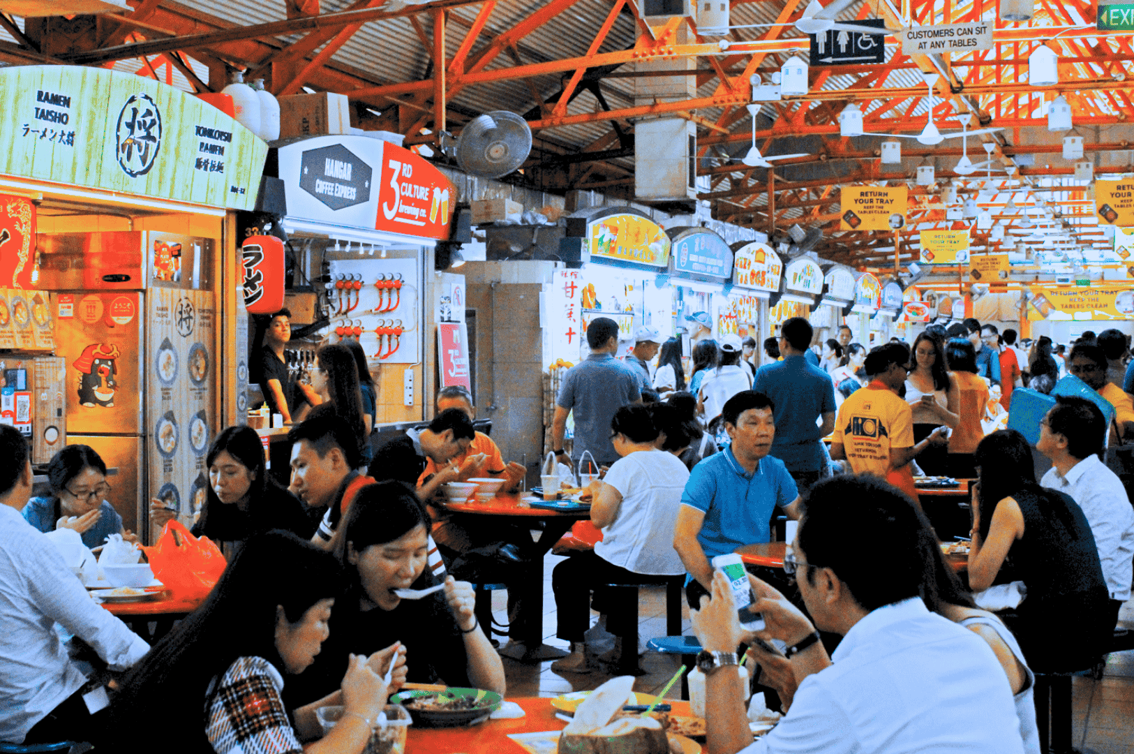 Bustling scene inside one of Singapore's iconic hawker centres, showcasing brightly lit food stalls and street food vendors serving mouthwatering food like char kway teow with flat rice noodles, chinese sausage, and dark soy sauce, hainanese chicken rice, nasi lemak with coconut milk, and other local dishes. Captured at a popular food centre such as Maxwell Food Centre, Lau Pa Sat, or Airport Road Food Centre, this vibrant open air food court near the Singapore River and central business district reflects real life hawker culture, where most stalls offer stir fried noodles, satay, chilli crab, roti prata, and malay dishes. Diners enjoy great food and drinks like teh tarik and coffee, surrounded by signage featuring local cuisine from Chinatown, Little India, and surrounding islands. A must visit spot for travel tips, hidden gems, and Anthony Bourdain-approved hawker food experiences in southeast Asia.