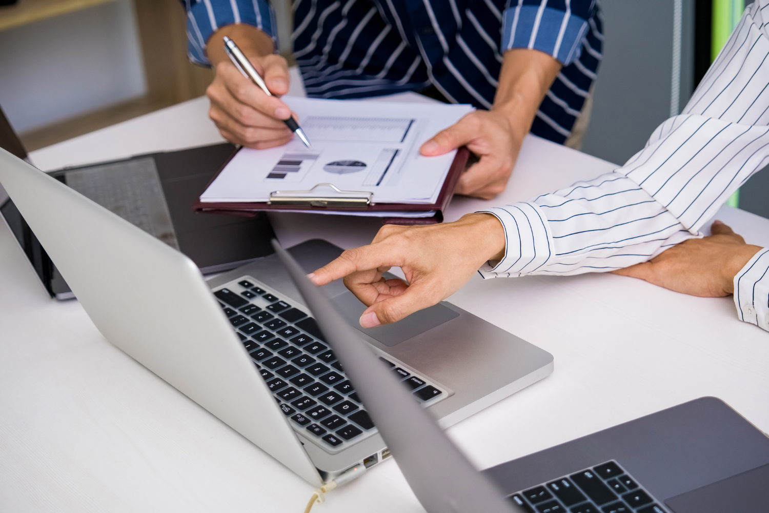 Business owner and professional business broker sitting at a desk while checking something on laptop.