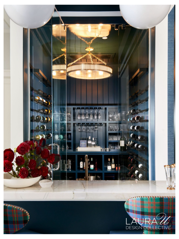 Glass-enclosed wine room with custom bottle storage, stemware shelving, and blue cabinetry designed by Laura U Design Collective.
