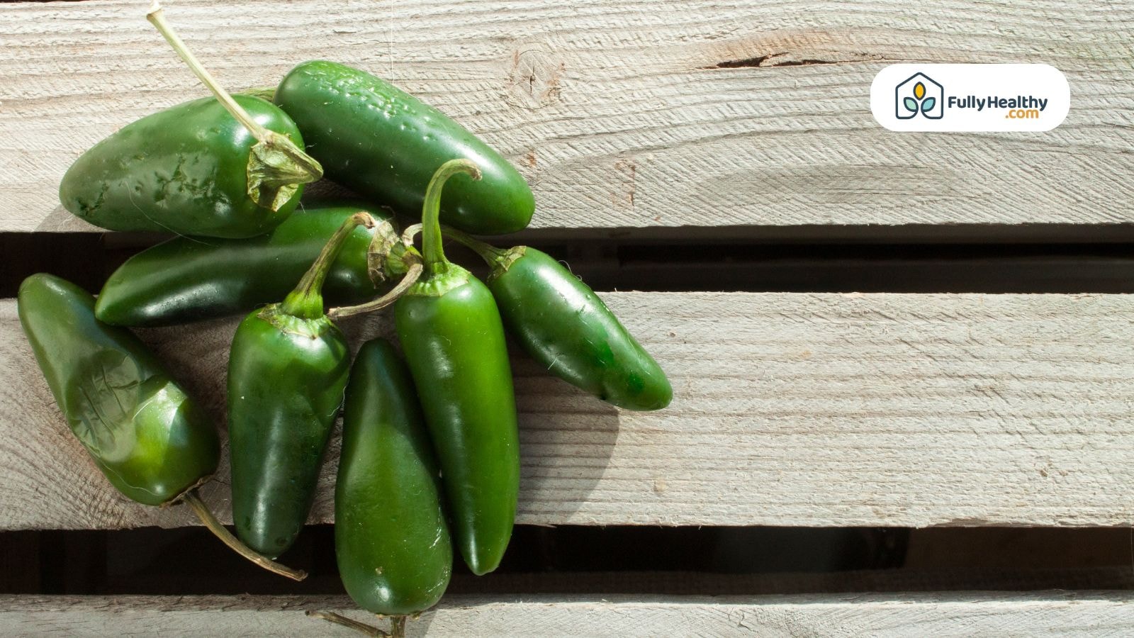 Green jalapeños on a rustic wooden surface in natural light