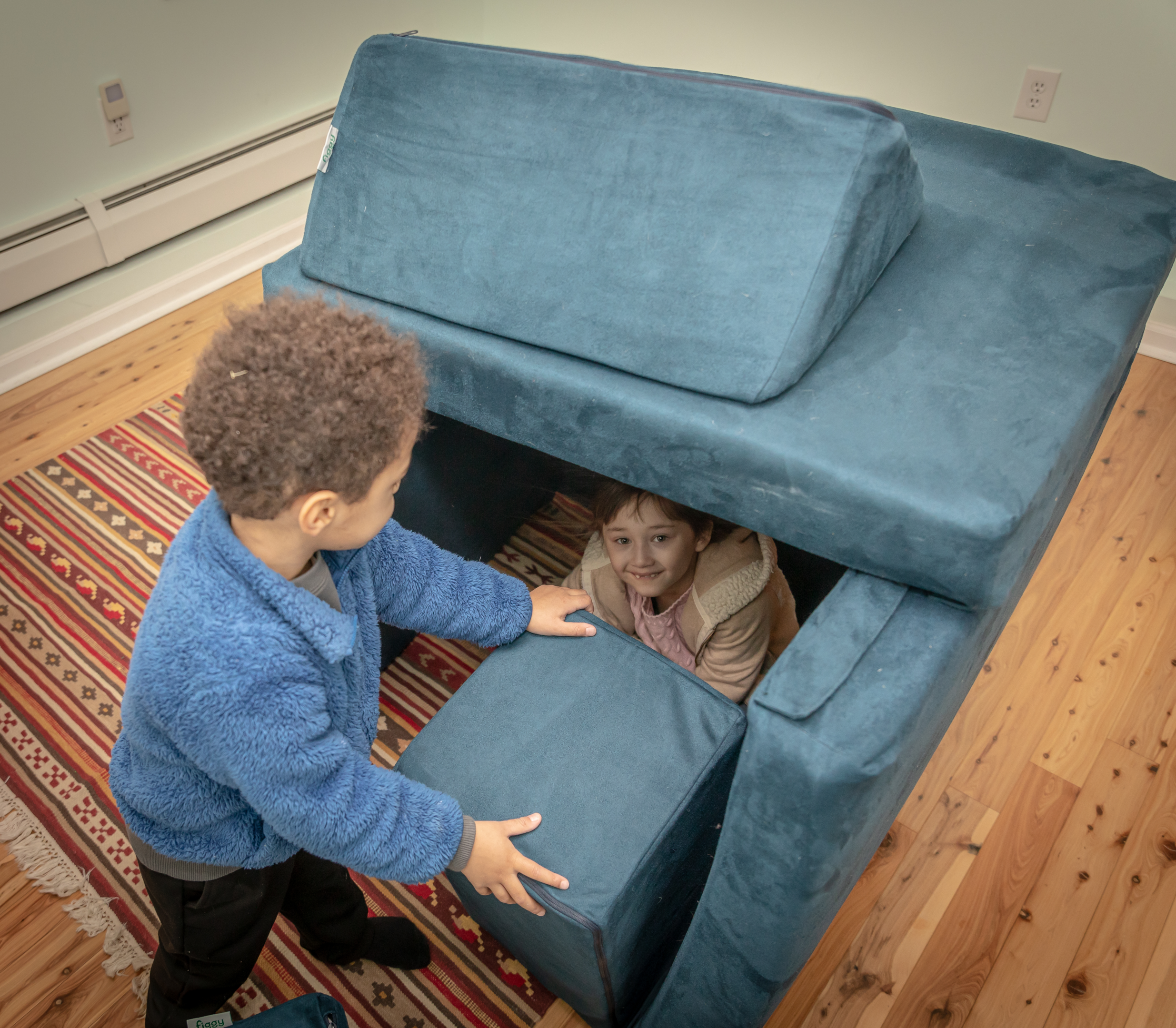 Two toddlers building a fort with a Figgy play couch