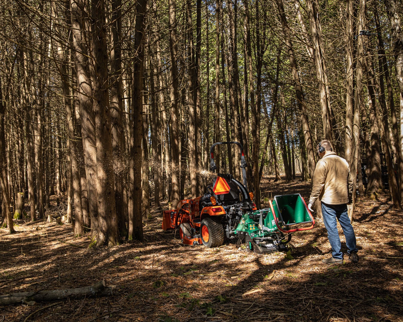 A woodlot owner using a wood chipper to clean up from seasonal tree trimming. 