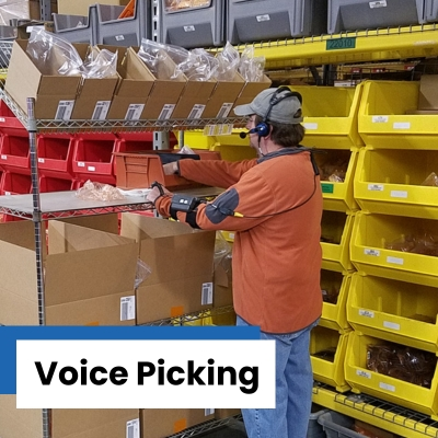 Man wearing a headset with a microphone placing items from shelving into a cart