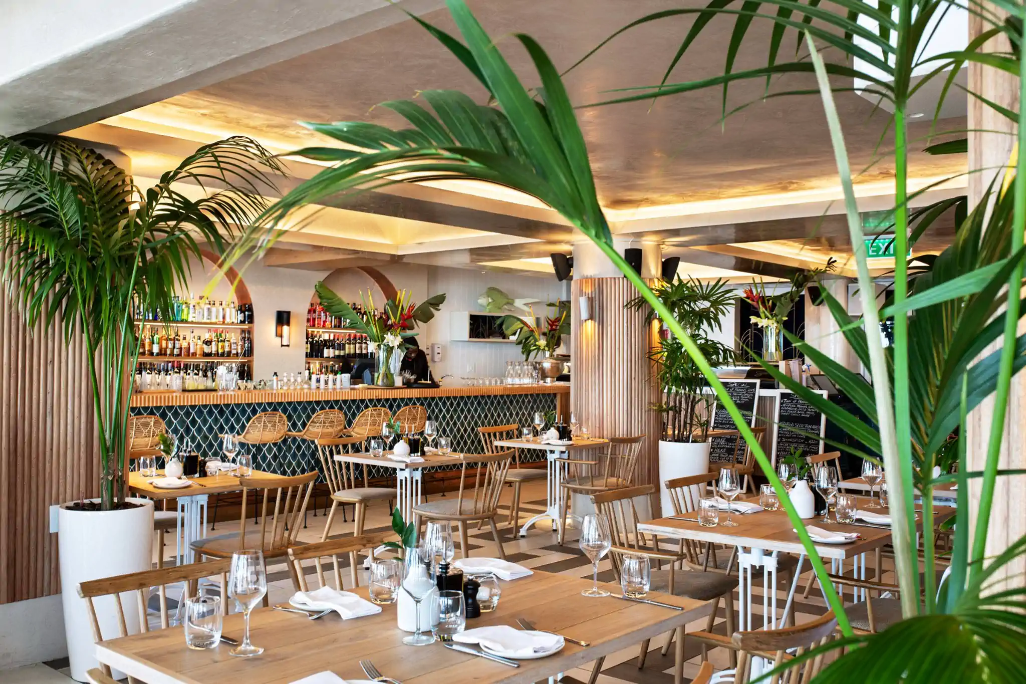 A stylish restaurant interior adorned with tropical plants and elegant dining settings. Fabulous Flowers and Gifts