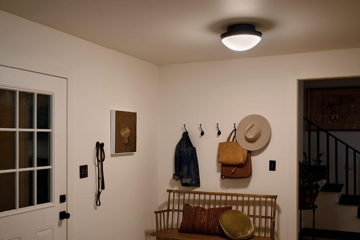 Black flush mount ceiling light with white glass shade in a warm traditional entryway