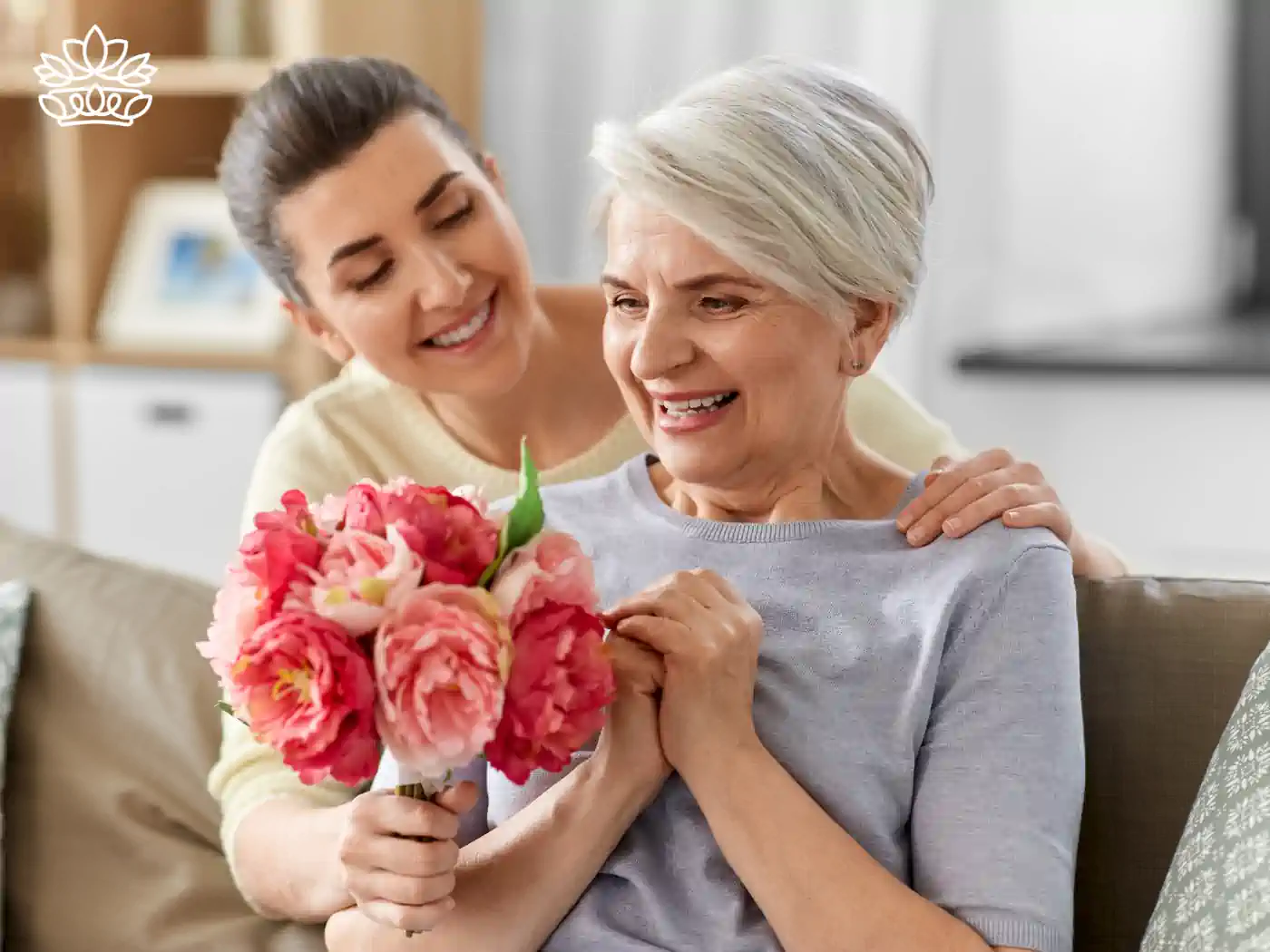 Image of an elderly woman receiving a pink flower bouquet from a younger woman, both smiling happily. Fabulous Flowers and Gifts - Luxury Flower Bouquets.