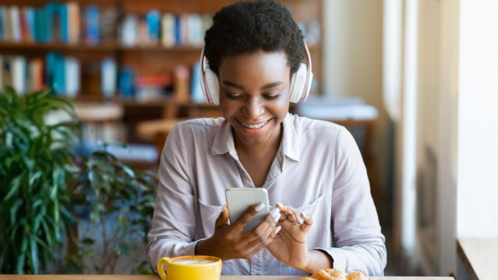Smiling woman enjoying coffee while enjoying valuable content on her smartphone, proving that a good content marketing strategy nurtures leads.