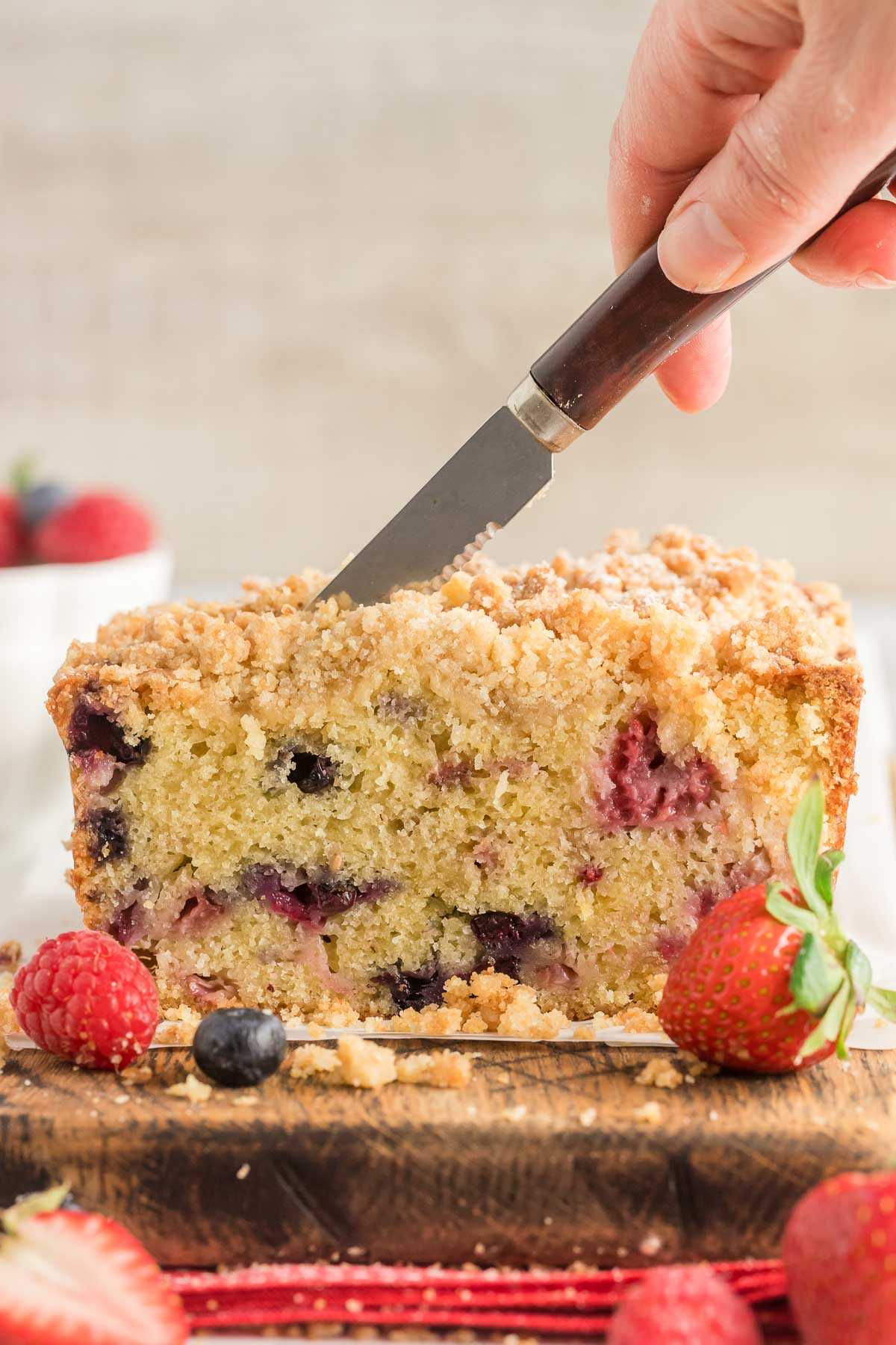 hand cutting a berry bread with a knife