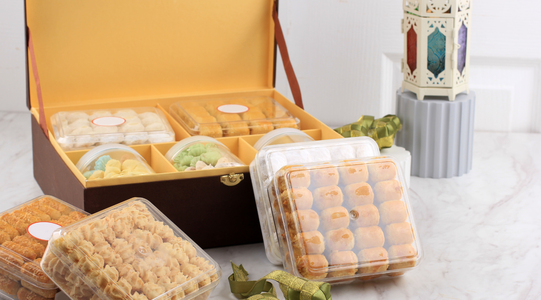 Assorted gourmet treats neatly arranged in a golden gift box on a marble countertop.